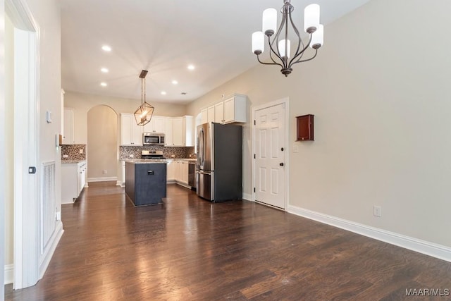 kitchen with arched walkways, a chandelier, appliances with stainless steel finishes, dark wood-style flooring, and decorative backsplash