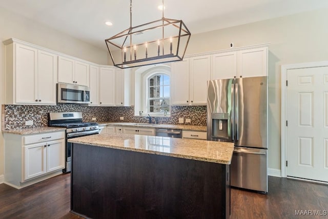 kitchen featuring light stone countertops, tasteful backsplash, white cabinets, a kitchen island, and stainless steel appliances