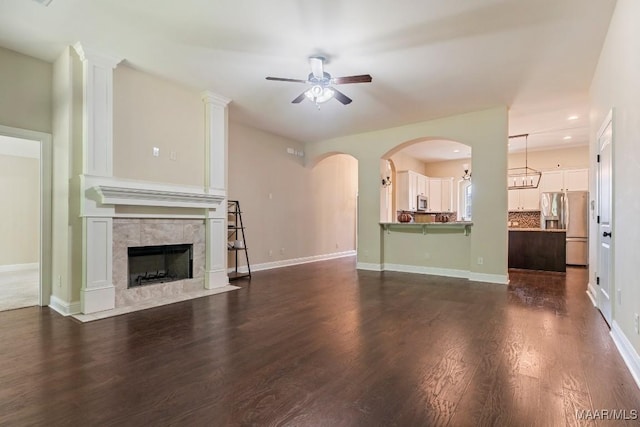 unfurnished living room with dark hardwood / wood-style flooring, a tile fireplace, and ceiling fan