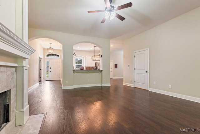 unfurnished living room with dark hardwood / wood-style floors, ceiling fan, and a fireplace