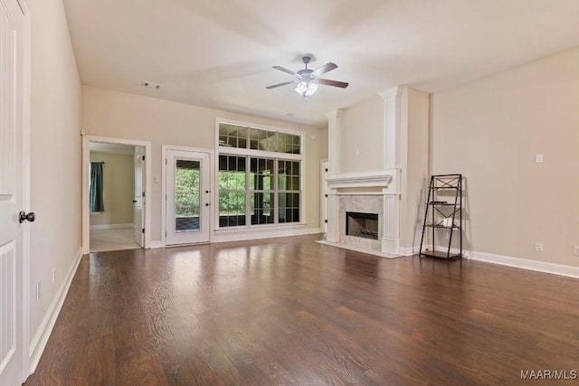 unfurnished living room with ceiling fan, baseboards, wood finished floors, and a fireplace