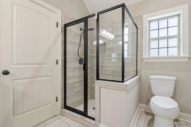 bathroom with toilet, baseboards, and a stall shower