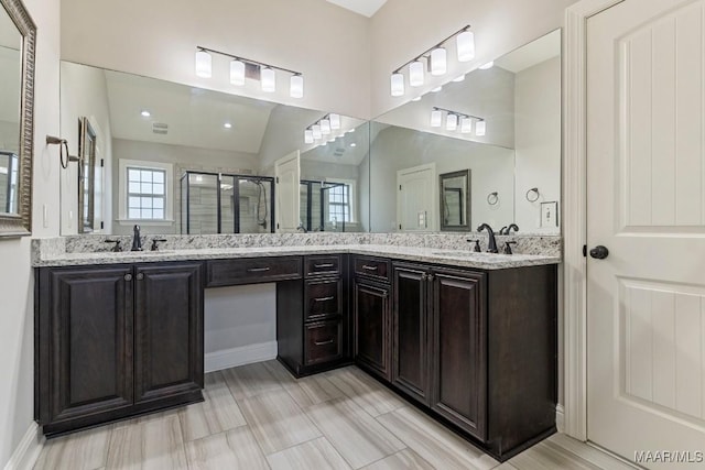 full bath with a sink, double vanity, a stall shower, and vaulted ceiling