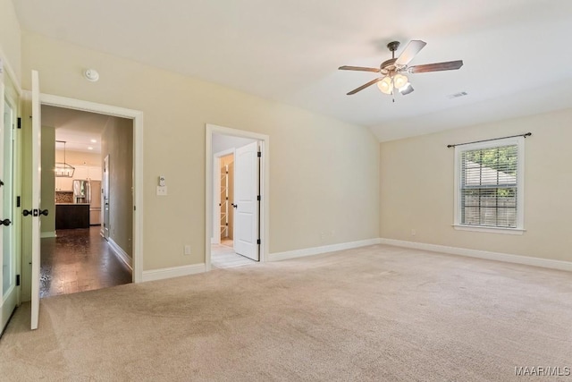 carpeted empty room with visible vents, baseboards, a ceiling fan, and vaulted ceiling