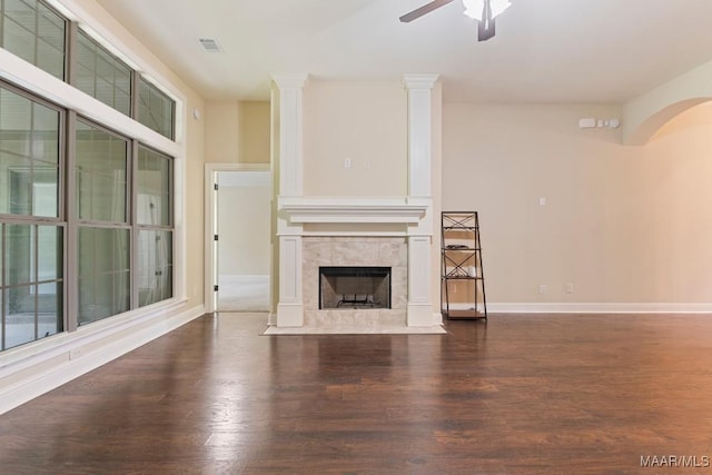 unfurnished living room featuring a tile fireplace, ceiling fan, visible vents, and wood finished floors
