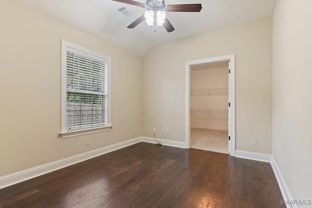 spare room featuring baseboards, dark wood-type flooring, visible vents, lofted ceiling, and ceiling fan