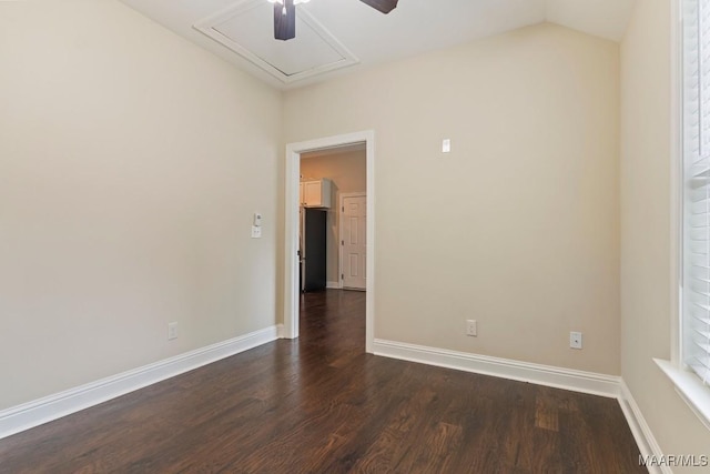 unfurnished room featuring dark wood-style floors, baseboards, attic access, and lofted ceiling