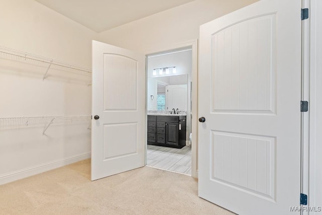 walk in closet with a sink and light carpet