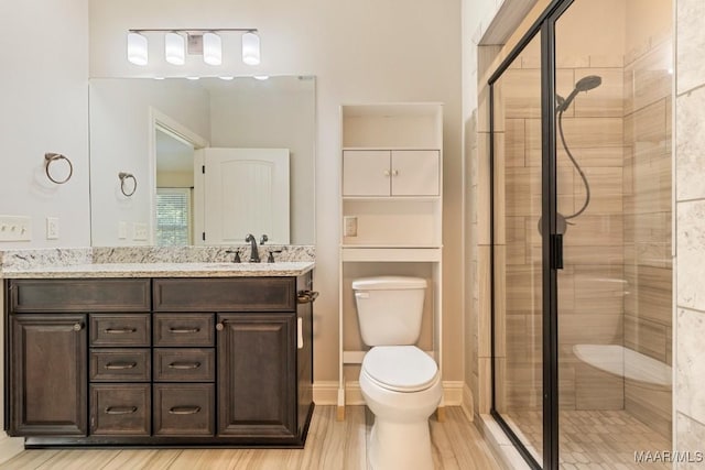 bathroom with a shower with door, vanity, wood-type flooring, and toilet