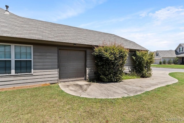 exterior space featuring an attached garage, a lawn, and roof with shingles