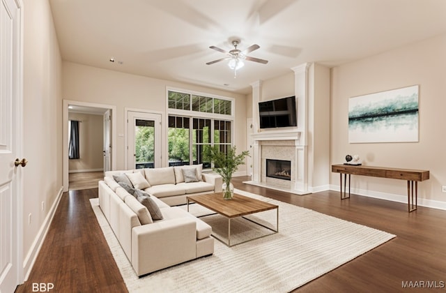 living area featuring wood finished floors, ceiling fan, a fireplace, and baseboards