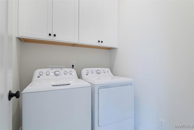 clothes washing area featuring cabinets and separate washer and dryer