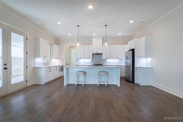 kitchen with a center island with sink, a kitchen breakfast bar, white cabinets, and appliances with stainless steel finishes