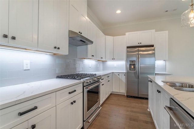 kitchen with white cabinetry, backsplash, hanging light fixtures, stainless steel appliances, and light stone counters