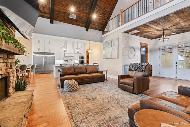 living room featuring high vaulted ceiling, a fireplace, beamed ceiling, light hardwood / wood-style floors, and wood ceiling