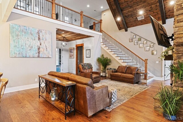 living room with a high ceiling, wood ceiling, and light hardwood / wood-style flooring