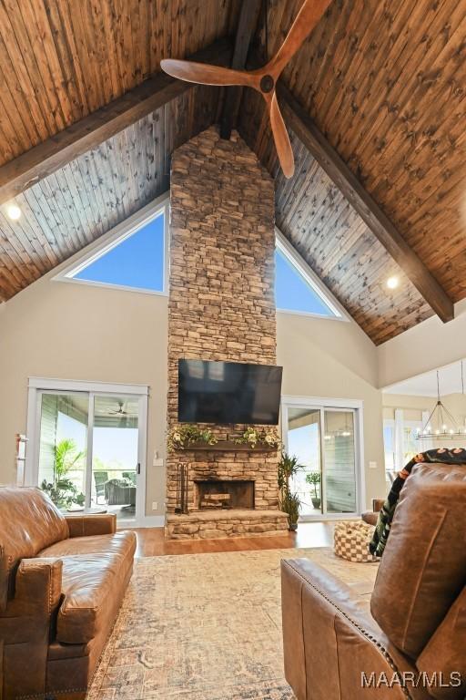 living room with beamed ceiling, a stone fireplace, hardwood / wood-style floors, and wooden ceiling