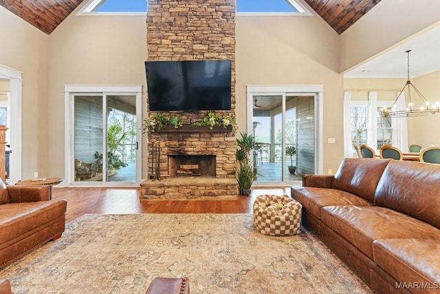 living room with wood-type flooring, high vaulted ceiling, a notable chandelier, and a fireplace