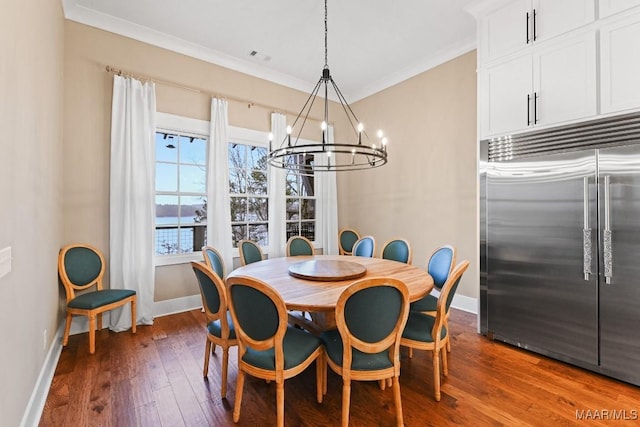 dining room featuring crown molding, a water view, a chandelier, and dark wood-type flooring