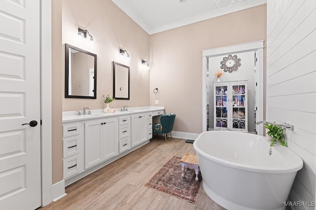 bathroom with vanity, wood-type flooring, ornamental molding, and a bathing tub