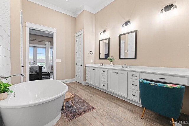 bathroom with wood-type flooring, a tub, ornamental molding, vanity, and french doors