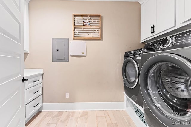 clothes washing area featuring independent washer and dryer, electric panel, cabinets, and light wood-type flooring