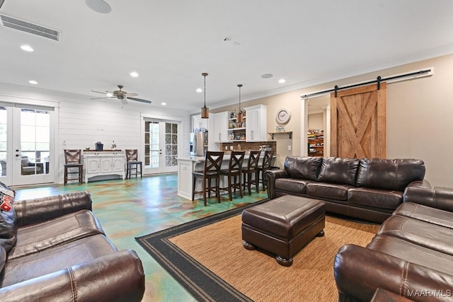 living room featuring french doors, ceiling fan, ornamental molding, and a barn door