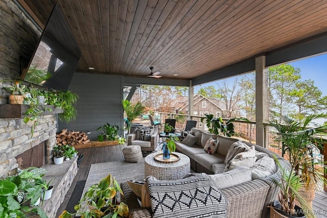 sunroom / solarium with ceiling fan, wooden ceiling, and an outdoor stone fireplace