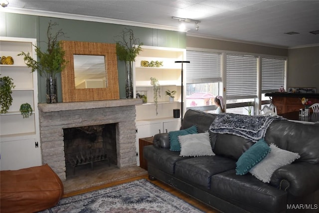 living room featuring crown molding, a stone fireplace, wood-type flooring, and built in shelves