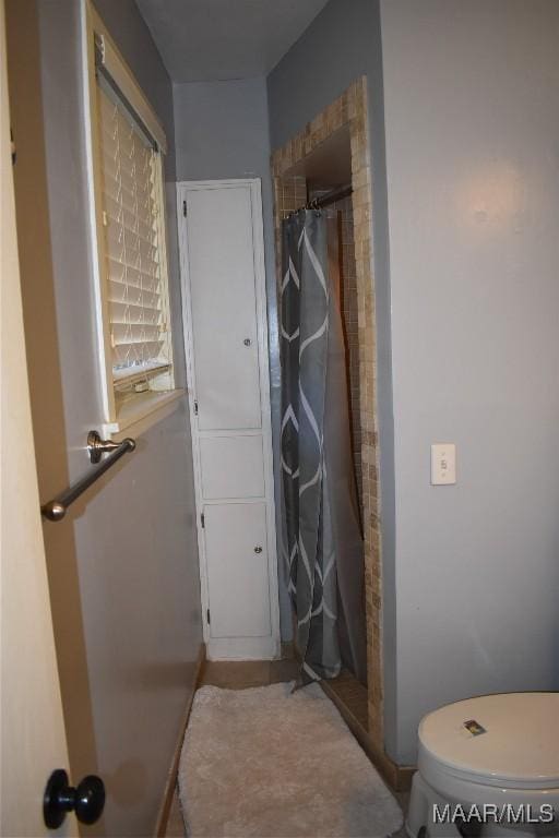 bathroom with curtained shower and toilet