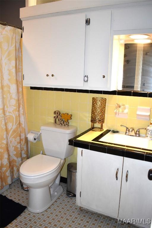 bathroom featuring tasteful backsplash, vanity, tile walls, and toilet