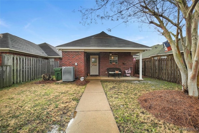 view of front of property featuring cooling unit, a patio area, and a front lawn