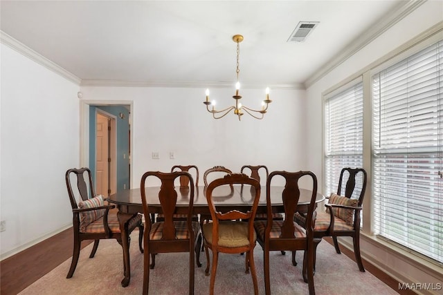 dining area with hardwood / wood-style flooring, ornamental molding, and a chandelier