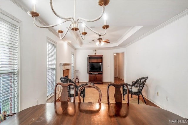 dining space featuring ceiling fan with notable chandelier, ornamental molding, a raised ceiling, and light hardwood / wood-style floors