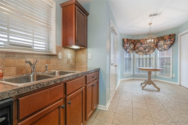 kitchen with plenty of natural light, decorative light fixtures, light tile patterned floors, and decorative backsplash