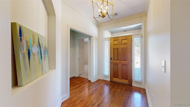 entryway featuring dark wood-type flooring, ornamental molding, and a chandelier