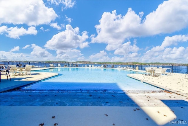 view of swimming pool featuring a water view and a patio