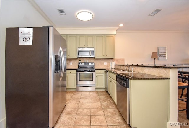 kitchen with appliances with stainless steel finishes, sink, a kitchen bar, light tile patterned floors, and kitchen peninsula