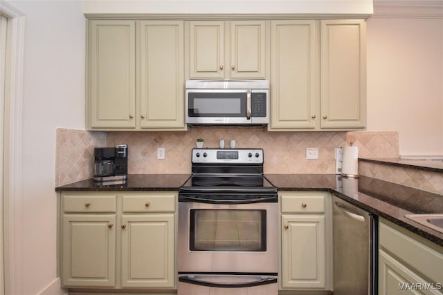 kitchen featuring stainless steel appliances, tasteful backsplash, cream cabinets, and dark stone counters