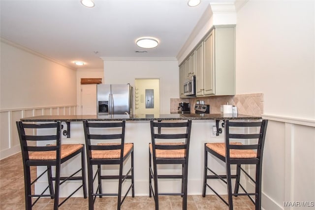 kitchen with stainless steel appliances, tasteful backsplash, ornamental molding, and dark stone counters