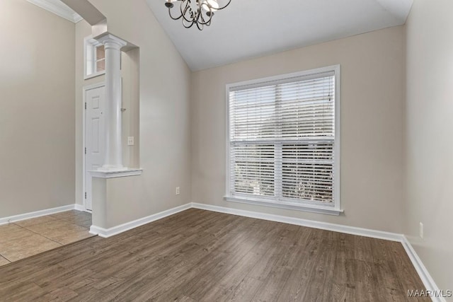 unfurnished room with lofted ceiling, wood-type flooring, an inviting chandelier, and ornate columns