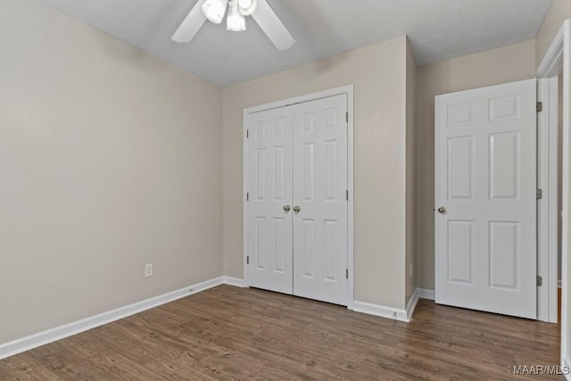 unfurnished bedroom with ceiling fan, dark hardwood / wood-style flooring, and a closet