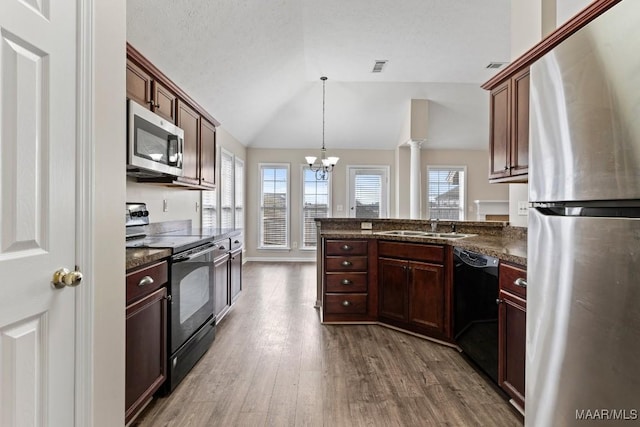 kitchen with sink, black appliances, dark hardwood / wood-style flooring, decorative light fixtures, and vaulted ceiling