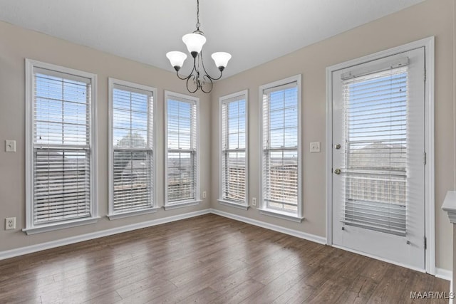 unfurnished dining area with dark hardwood / wood-style flooring, a notable chandelier, and a wealth of natural light