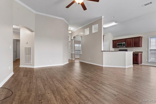 unfurnished living room with crown molding, ceiling fan, a healthy amount of sunlight, and dark hardwood / wood-style floors