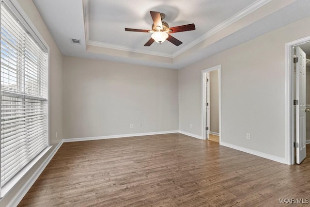 spare room featuring a raised ceiling, crown molding, dark wood-type flooring, and ceiling fan