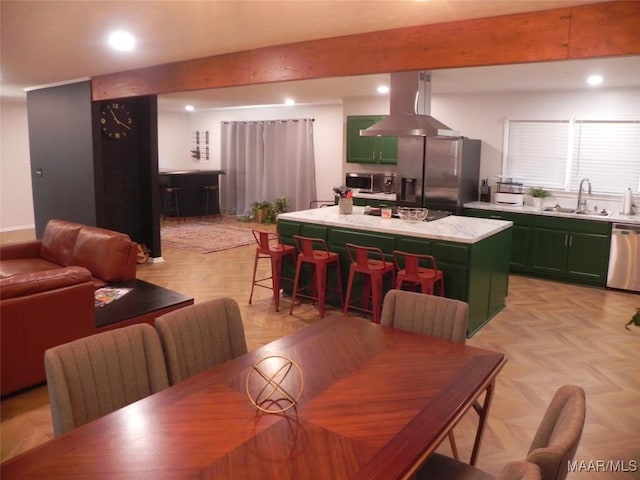 dining area with sink, beamed ceiling, and light parquet flooring