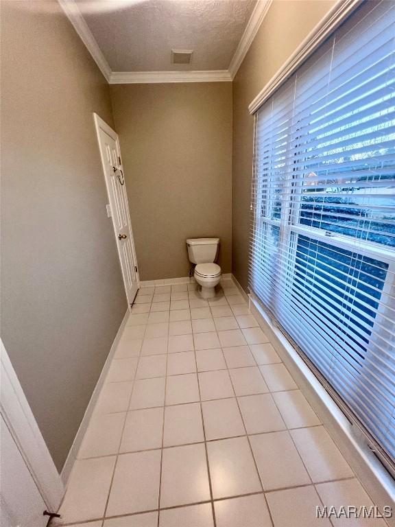 bathroom with crown molding, tile patterned floors, toilet, and a textured ceiling