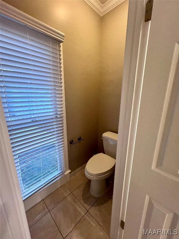 bathroom with crown molding, toilet, and tile patterned flooring