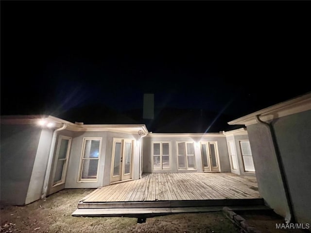 back house at night featuring a deck